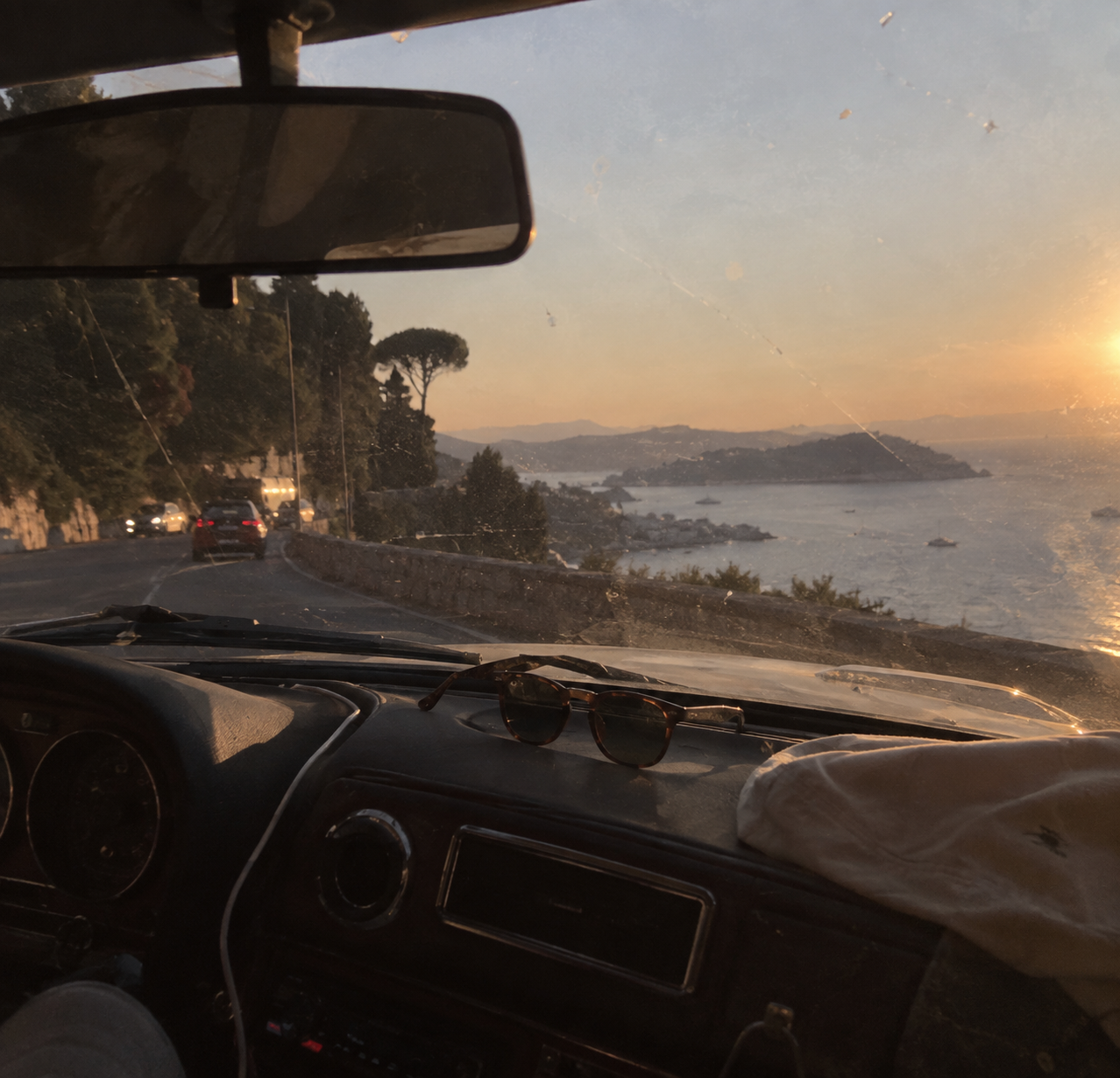 Coastal road at sunset, sunglasses on the dashboard